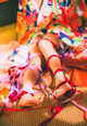 A woman in a colorful kimono sitting on the floor with her feet tied up.