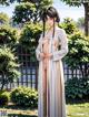 A woman in a white kimono standing in a garden.