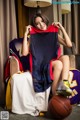 A woman sitting on a chair holding a basketball jersey.