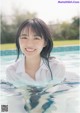 A woman in a white shirt is smiling in a pool.