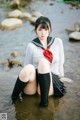 A woman in a school uniform sitting in the water.