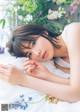 A woman laying on a bed with flowers in the background.