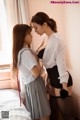 A couple of women standing next to each other on a bed.