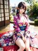 A woman in a kimono sitting on a red blanket.