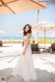 A woman in a white dress standing on a beach.