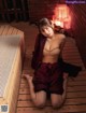 A woman sitting on a wooden floor in a sauna.