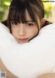 A young woman laying on top of a white pillow.