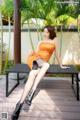 A woman in an orange dress sitting on a bench.