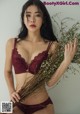 A woman in a red bra and panties holding a bunch of flowers.